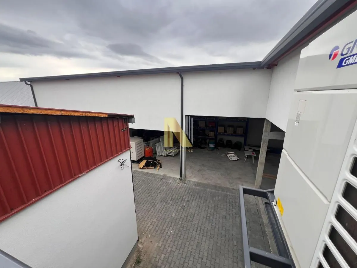 View of the exterior of the building with a paved courtyard and auxiliary rooms.