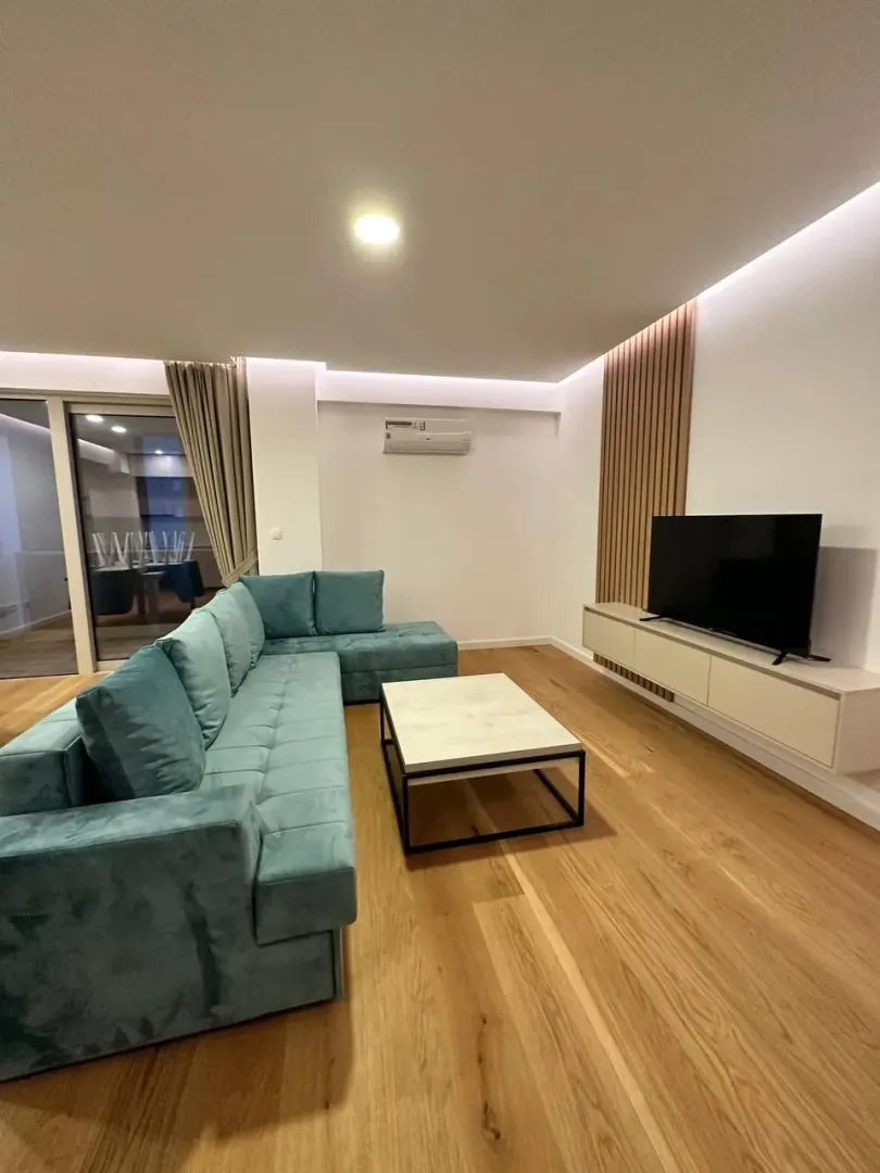 Modern living room with a turquoise sectional sofa and a TV cabinet.
