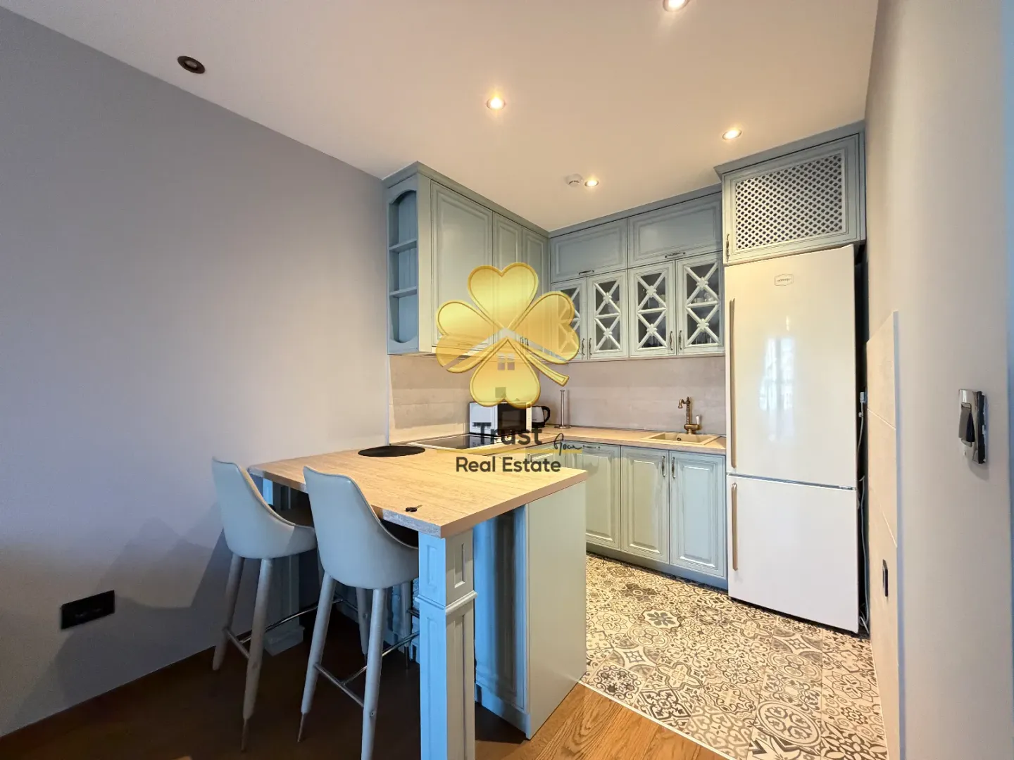 Modern kitchen with light-colored cabinetry, a breakfast bar, and bar stools.