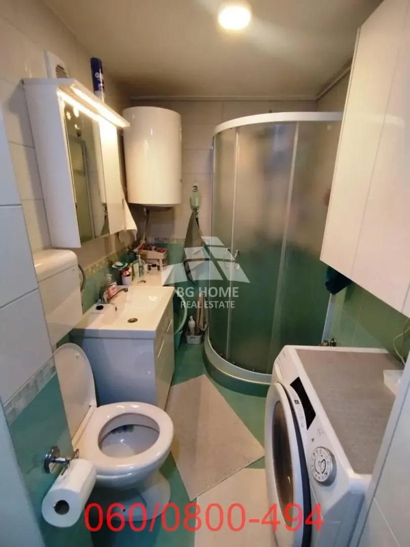Manje kupatilo sa tuš kabinom, umivaonikom, WC šoljom i veš mašinom.