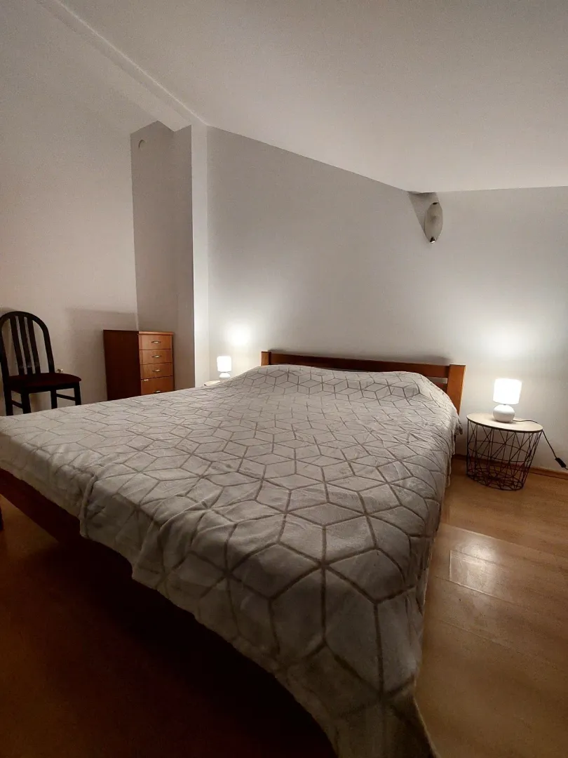 Spacious bedroom with a double bed, bedside lamps, and a wooden chest of drawers.