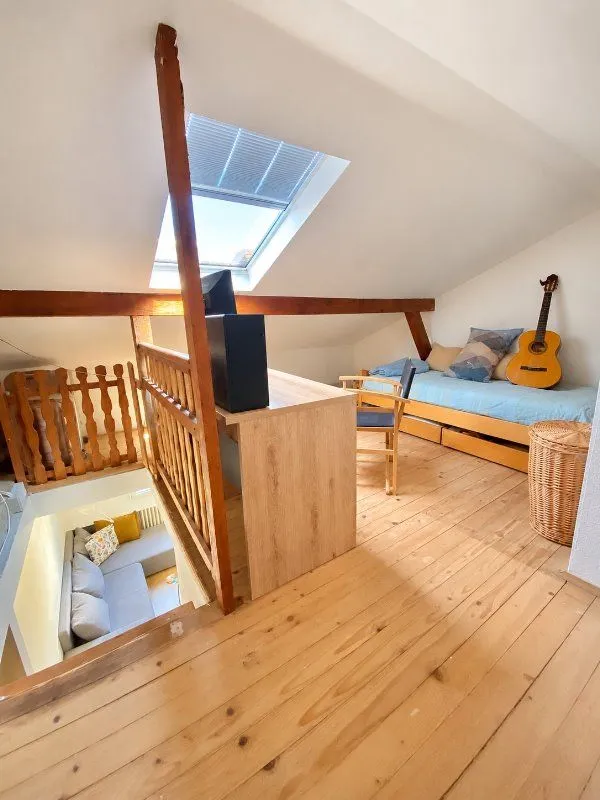 Attic space with a bed, desk, and skylight.