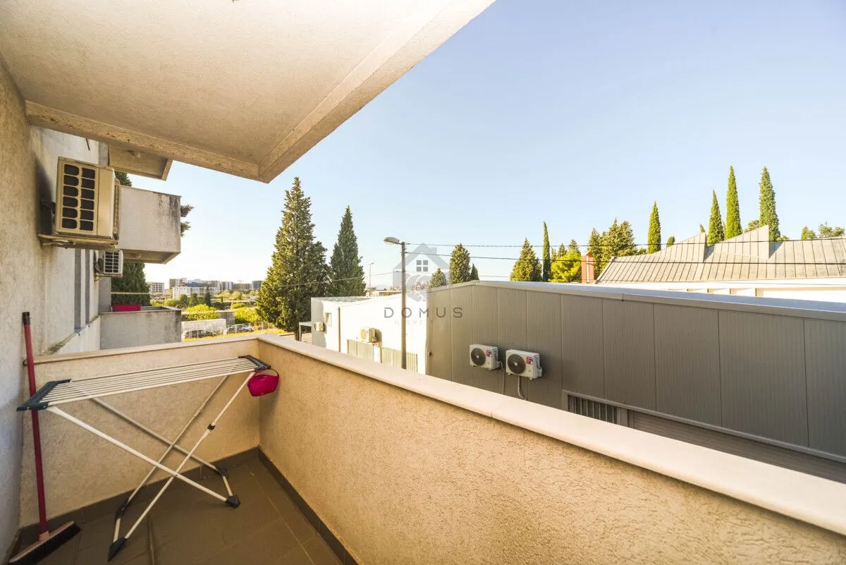Small covered balcony with a clothes drying rack and a view of the surroundings.