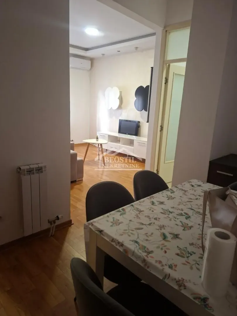 Pogled iz trpezarije na dnevnu sobu sa garniturom i televizorom.