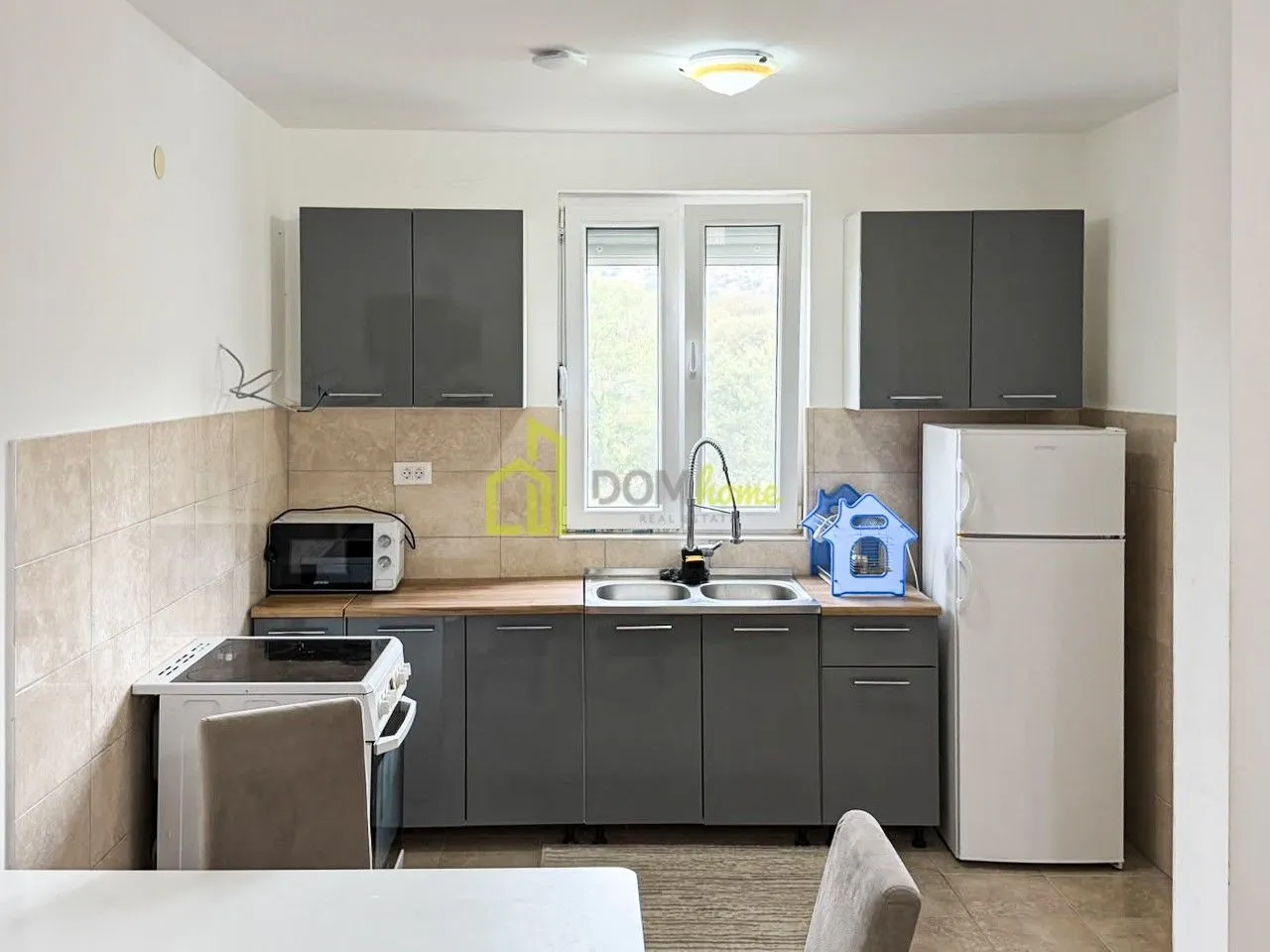 Kitchen with grey cabinets, sink, stove, and refrigerator.