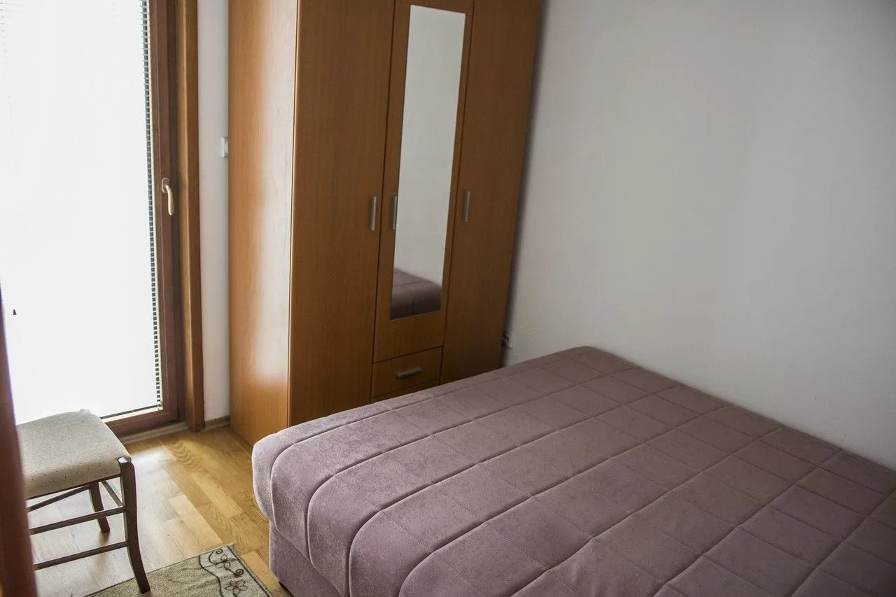 Jednostavna spavaća soba sa krevetom i drvenim ormarom.