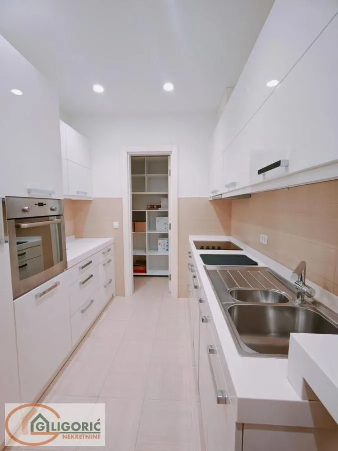 Modern white kitchen with a sink, built-in oven, and cooktop.