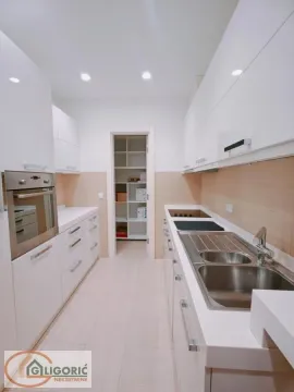 Modern white kitchen with a sink, built-in oven, and cooktop. - image 13