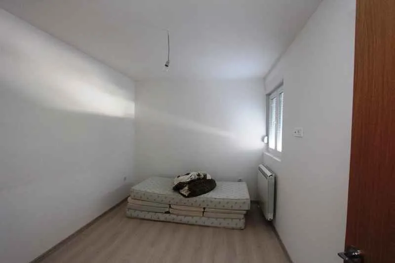 Prazna prostorija sa madracem na podu i bijelim zidovima.
