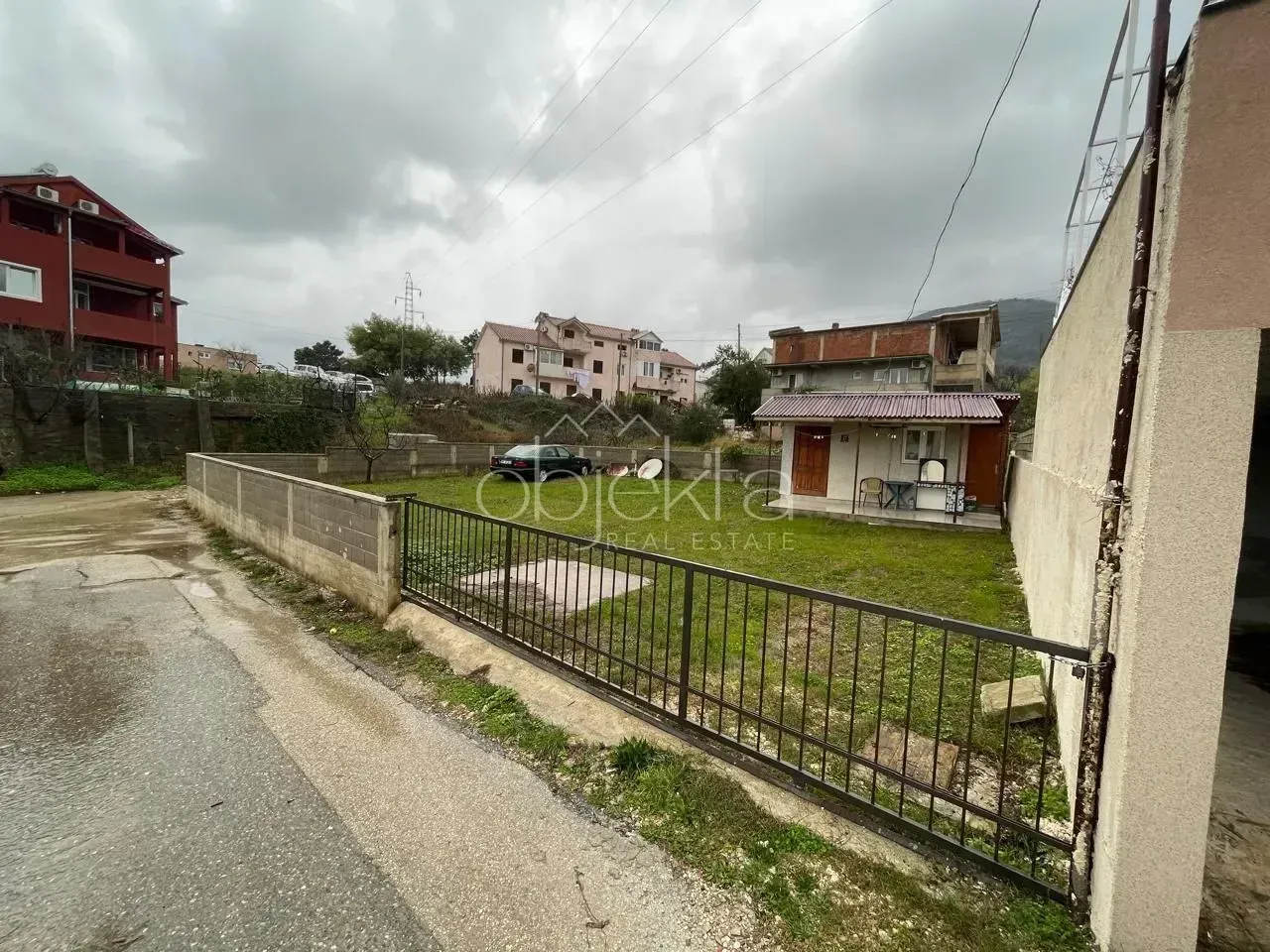 Pogled na dvorište i kuću sa ogradom i kapijom.