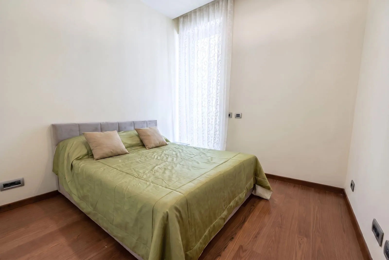 Furnished bedroom with a double bed and wooden flooring.