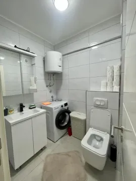 Compact bathroom equipped with a sink, toilet, washing machine, and water heater. - image 3