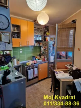 Kuhinja sa narandžastim elementima i trpezarijskim stolom. - image 9