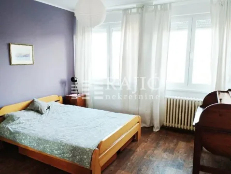 Nameštena spavaća soba sa bračnim krevetom, prozorima i drvenim podom. - image 4