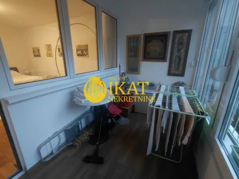 Enclosed balcony with a clothes drying rack and decorative pictures on the wall. - image 7