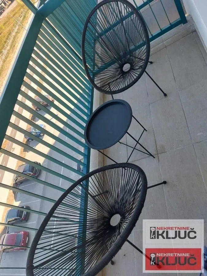 Manji namešteni balkon sa stolom i dve stolice.