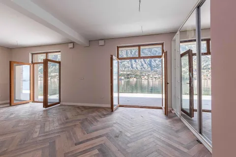Prazna prostorija sa drvenim podom i otvorenim pogledom na more i planine kroz balkonska vrata. - image 62