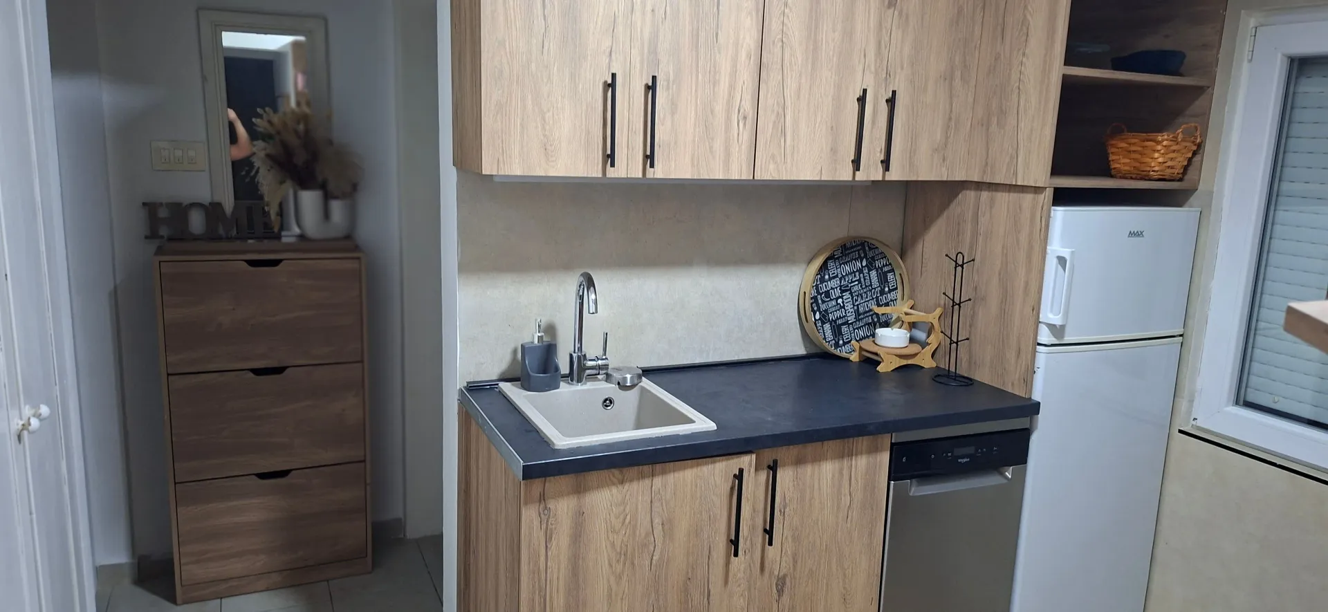 Small kitchen with wooden elements, sink, and integrated refrigerator.