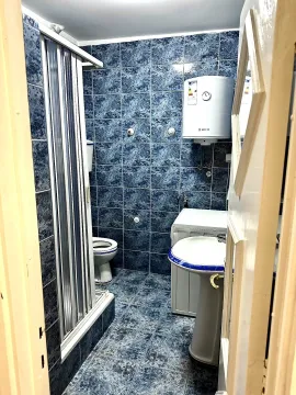 Kupatilo sa plavim pločicama, tuš kabinom i veš mašinom. - image 19