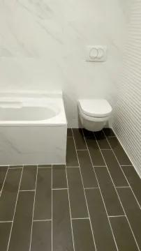 Moderno kupatilo sa bijelom kadom i tamnim podnim pločicama. - image 7