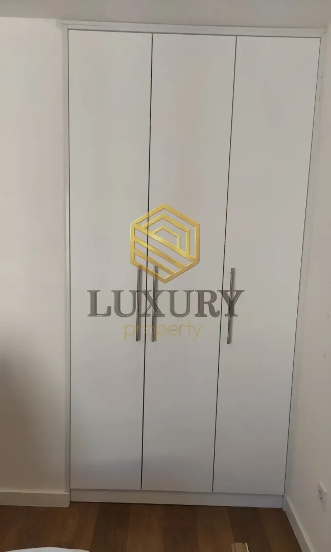 Bijeli ugradni garderober sa metalnim ručkama u sobi.