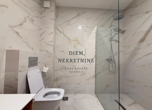 Modernly equipped bathroom with a walk-in shower and marble tiles.