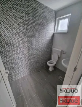 Smaller bathroom with a toilet, washbasin, and decorative wall tiles. - image 5