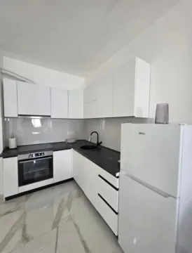 Moderna bijela kuhinja sa crnom radnom površinom i ugradnim aparatima. - image 4