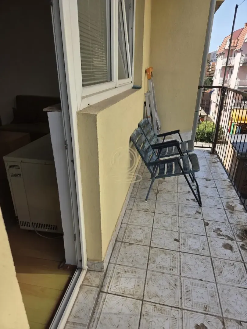 Manji popločani balkon sa stolicama i pogledom na okolne zgrade.