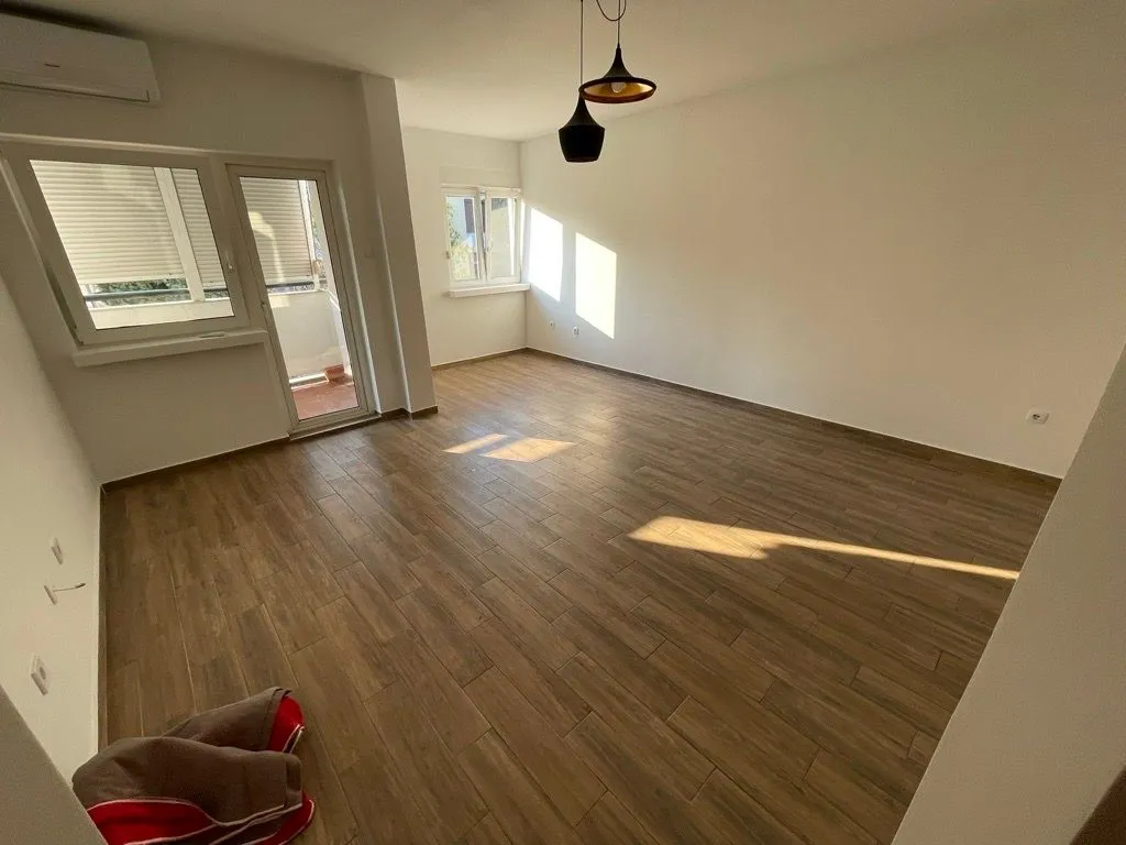Empty living room with wood-look tile flooring and access to the terrace.