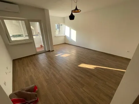 Empty living room with wood-look tile flooring and access to the terrace. - image 2