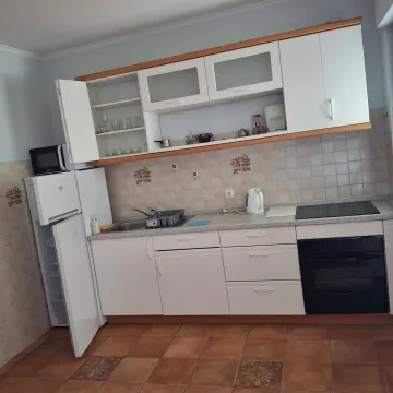 Manja opremljena kuhinja sa bijelim elementima i otvorenim vratima frižidera i gornjeg elementa. - image 2