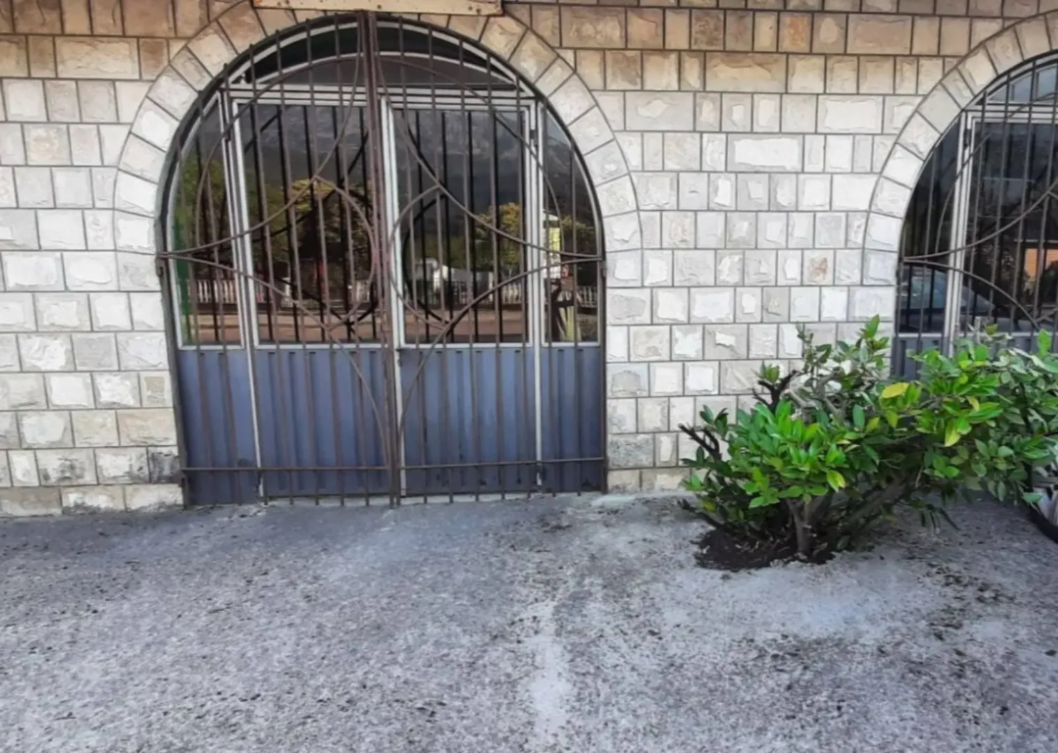 Exterior of the house with stone facade and barred entrance door.