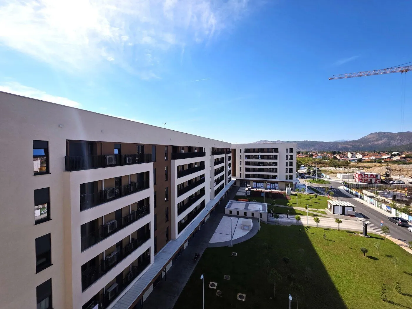 Spoljašnji pogled na moderne stambene zgrade sa uređenim dvorištem.