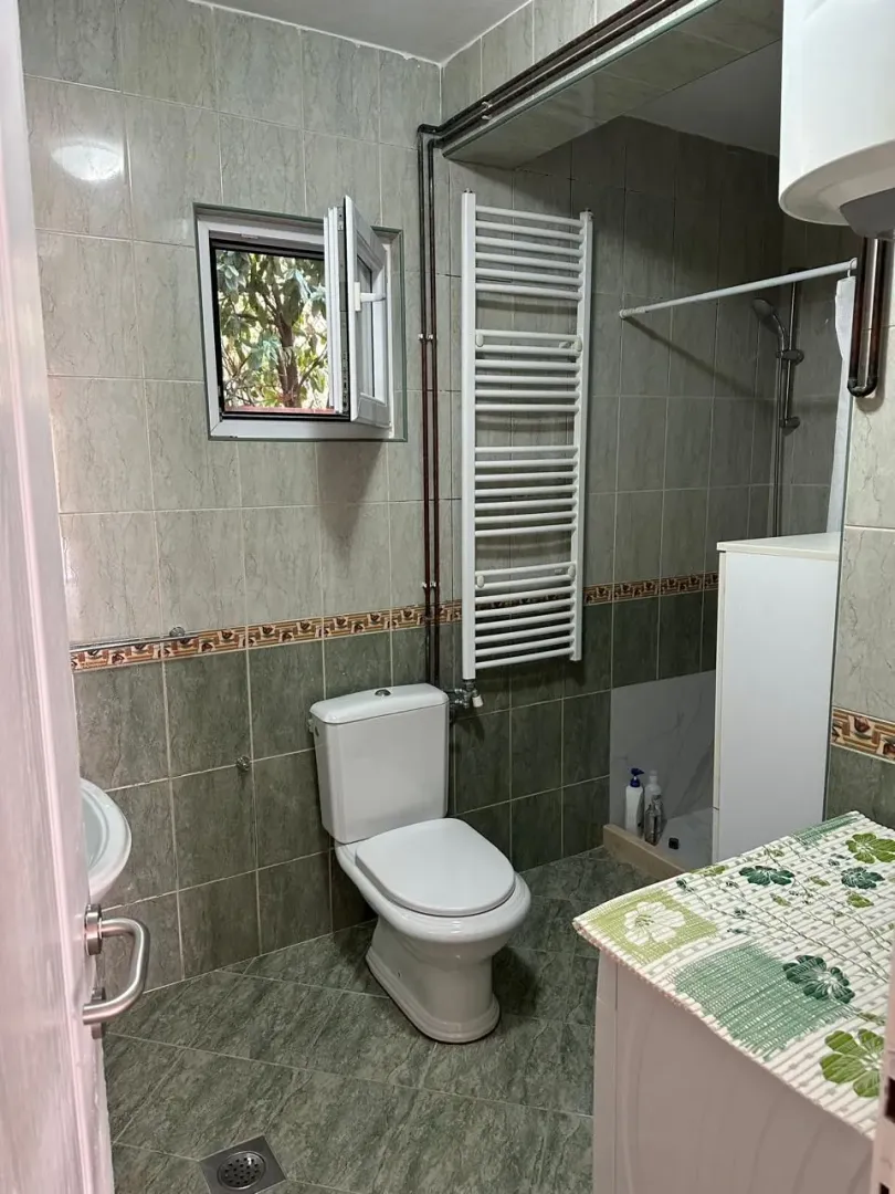 Smaller tiled bathroom with a toilet, shower cabin, and towel radiator.