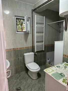 Smaller tiled bathroom with a toilet, shower cabin, and towel radiator. - image 6