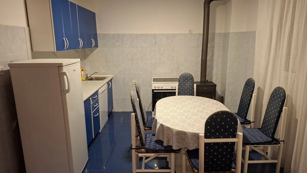 Kitchen with dining area equipped with blue cabinetry and a wood stove.