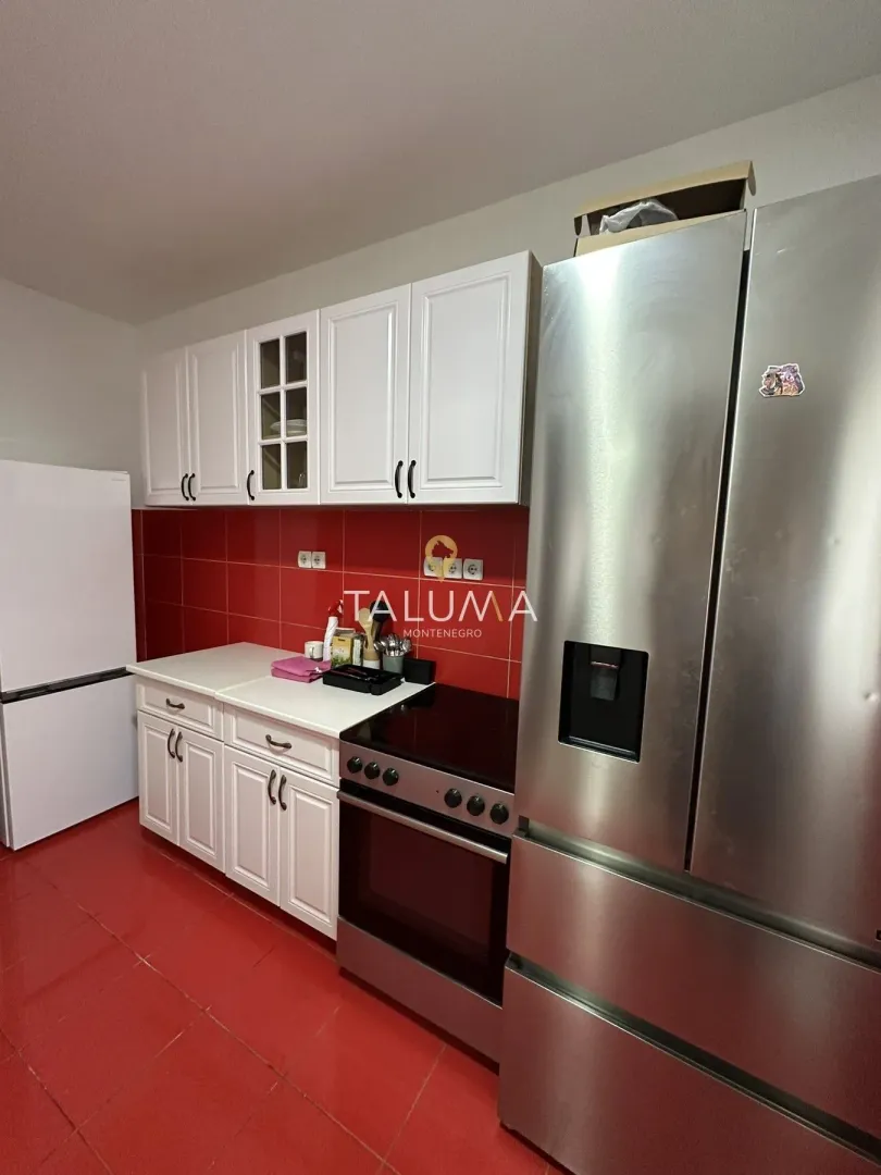 Kitchen with white cabinetry, red tiles, and a stove.