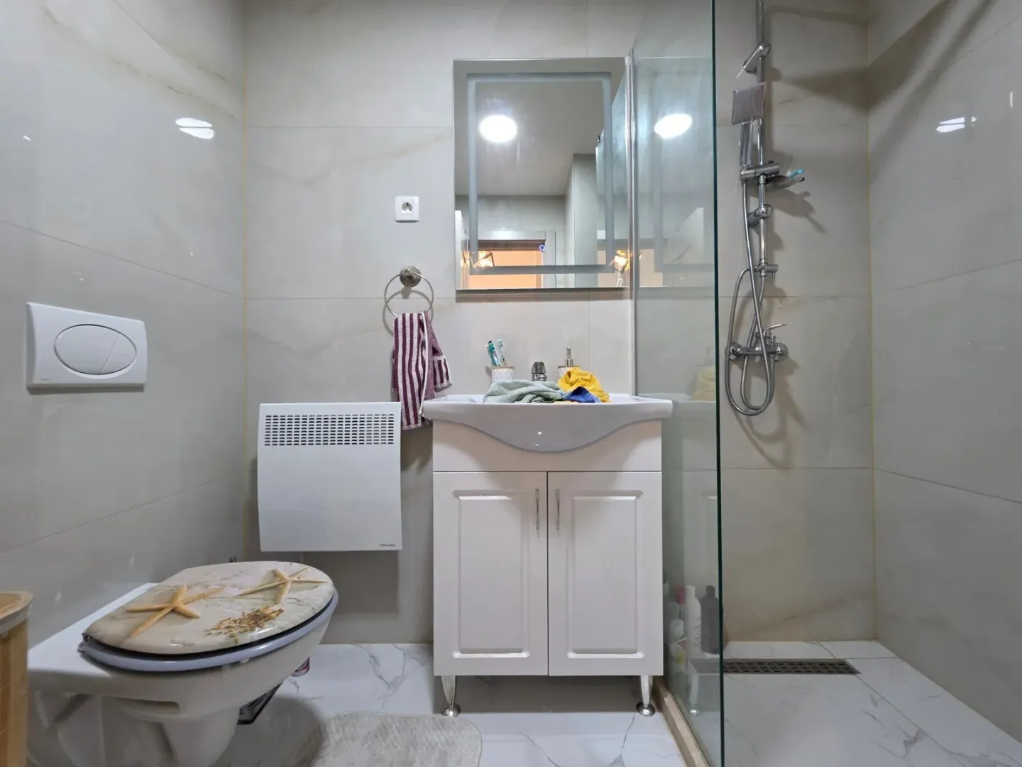 Moderno opremljeno kupatilo sa umivaonikom, WC šoljom i tuš kabinom.