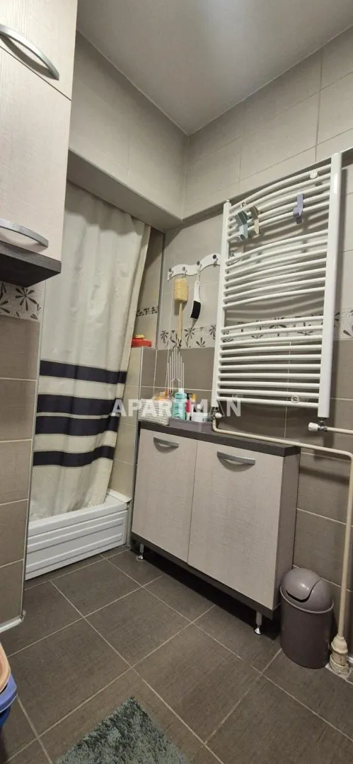 Smaller bathroom with a shower cabin, cabinet, and towel radiator.