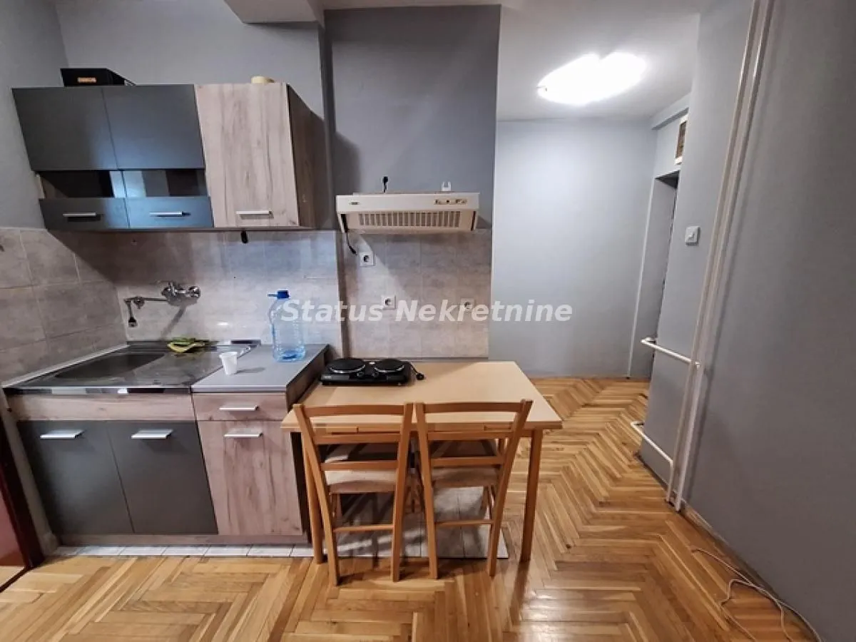 Manja kuhinja sa drvenim elementima i trpezarijskim stolom sa stolicama.
