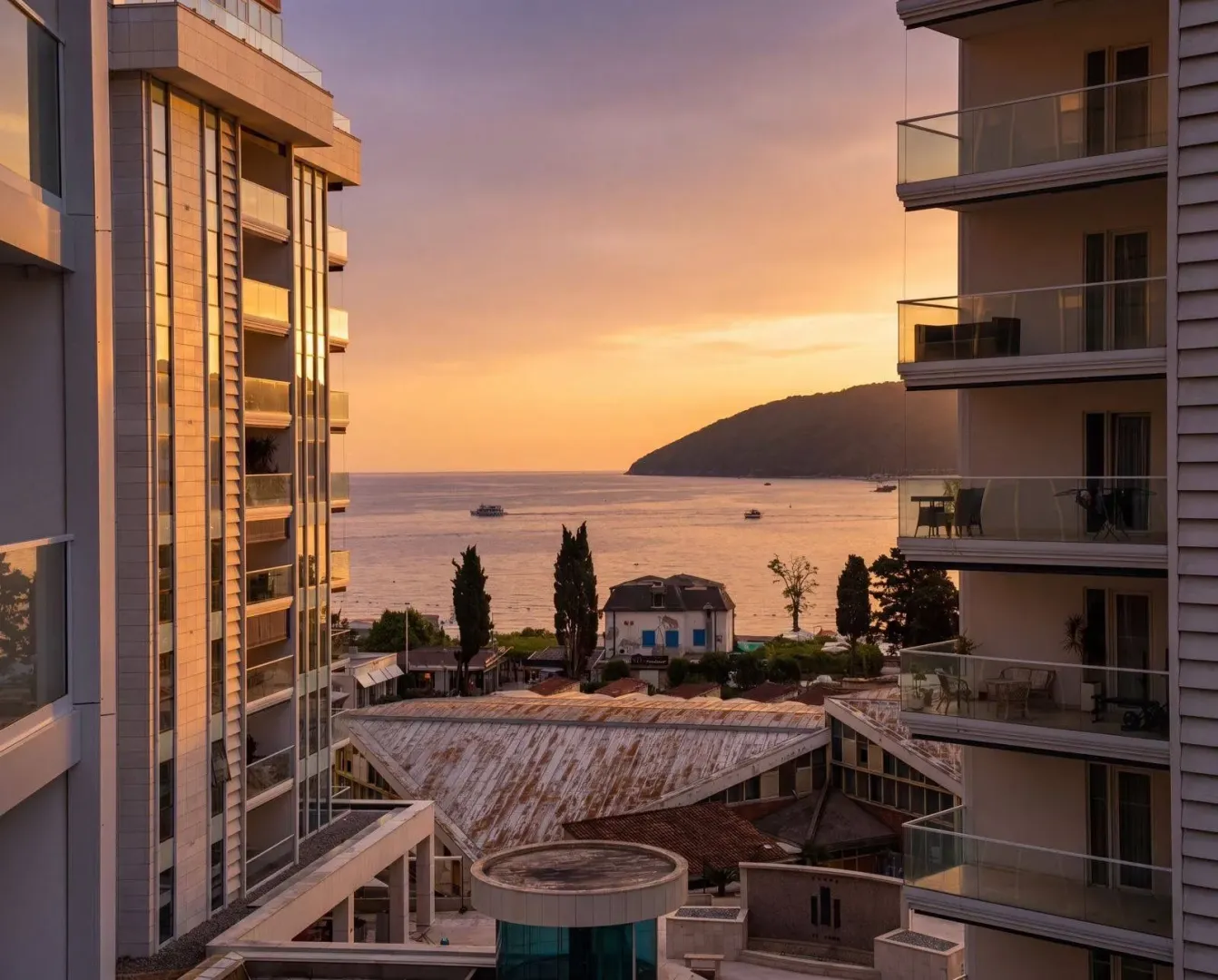 Pogled na more i okolne zgrade sa terase tokom zalaska sunca.
