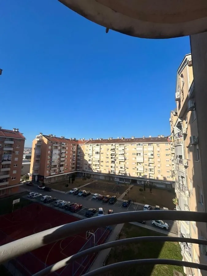 Pogled sa terase na dvorište zgrade, parking i igralište.