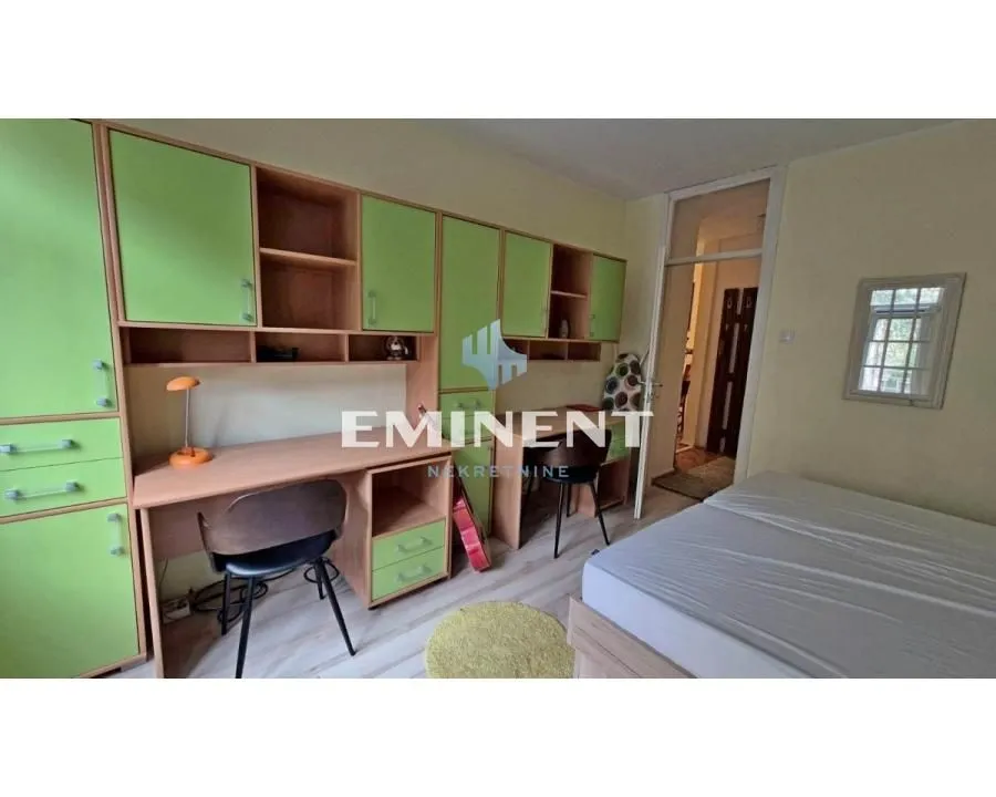 Children's bedroom with a bed, desk, and green wardrobes.