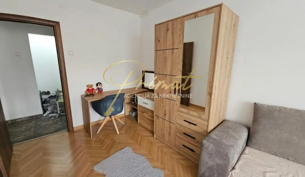 Small bedroom with a bed, wooden wardrobe, and a desk.
