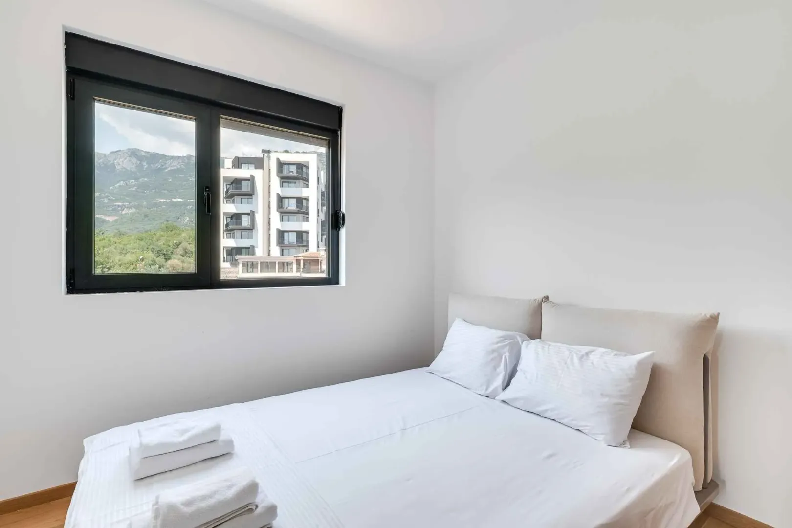 Bright bedroom with a double bed and a view through the window.