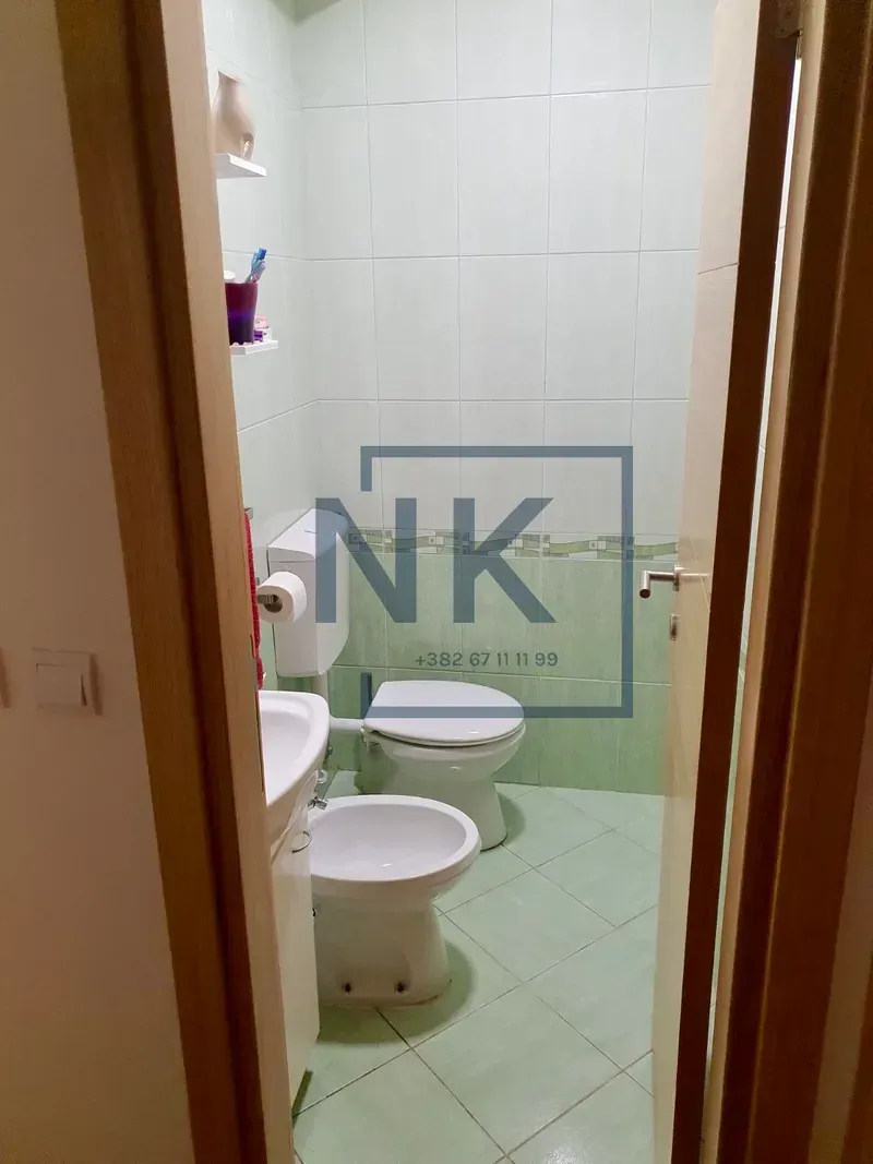 Smaller bathroom tiled in green with a toilet, bidet, and washbasin.