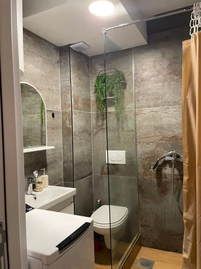 Modern bathroom with a walk-in shower, washbasin, and toilet.