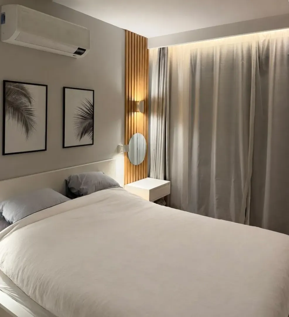 Furnished bedroom with a double bed, curtains, and decorative wooden wall panels.