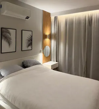 Furnished bedroom with a double bed, curtains, and decorative wooden wall panels. - image 8